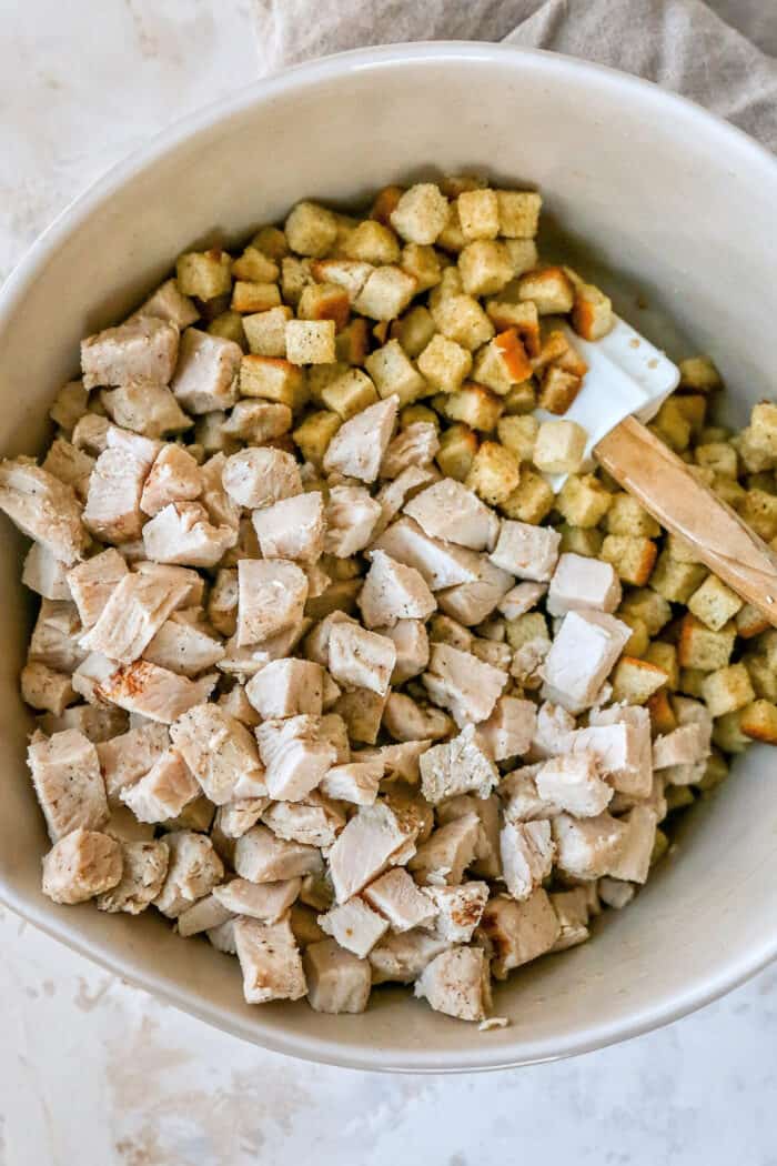 This hearty leftover turkey casserole recipe with sage, thyme, cream of chicken, and crispy stuffing is an easy way to clean out the fridge. Adding the turkey to the bowl with buttery stuffing.