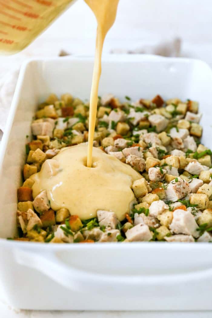 This hearty leftover turkey casserole recipe with sage, thyme, cream of chicken, and crispy stuffing is an easy way to clean out the fridge. Pouring the soup mixture over the first layer of turkey and stuffing.