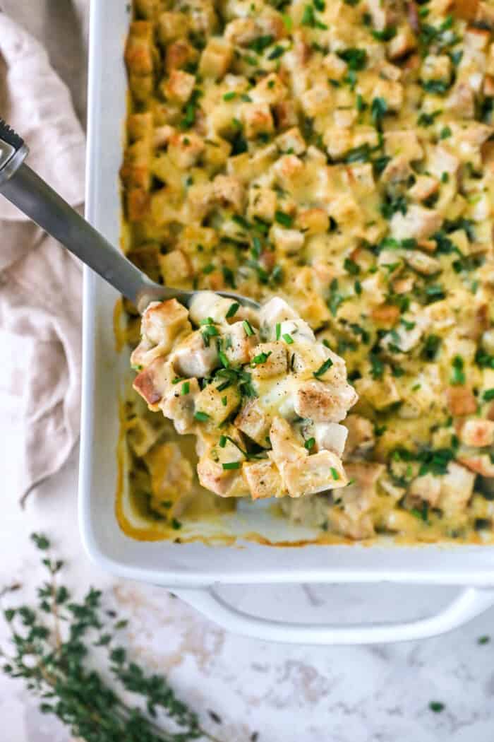 This hearty leftover turkey casserole recipe with sage, thyme, cream of chicken, and crispy stuffing is an easy way to clean out the fridge. Close-up of a creamy spoonful of casserole with stuffing, diced turkey, cream of chicken, and herbs.