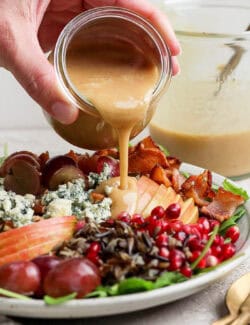 Pouring maple-Dijon dressing over the salad.