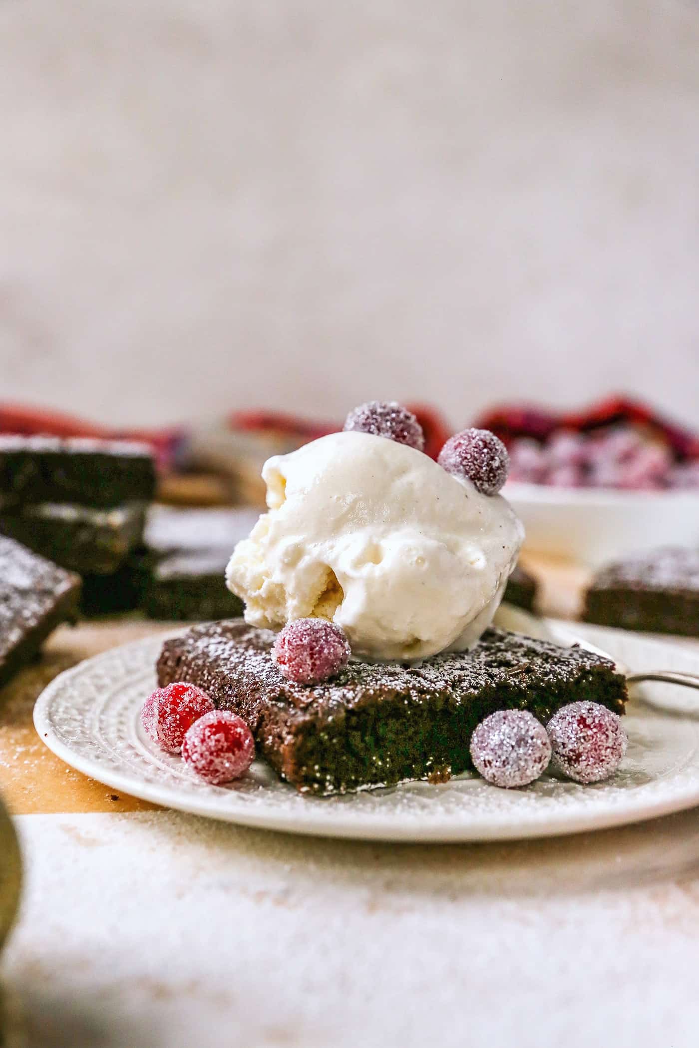 Gingerbread brownies are moist and fudgy, with a touch of molasses and warm spices. A fun holiday twist on a traditional brownie recipe! gingerbread brownie with a scoop of vanilla ice cream and sugared cranberries