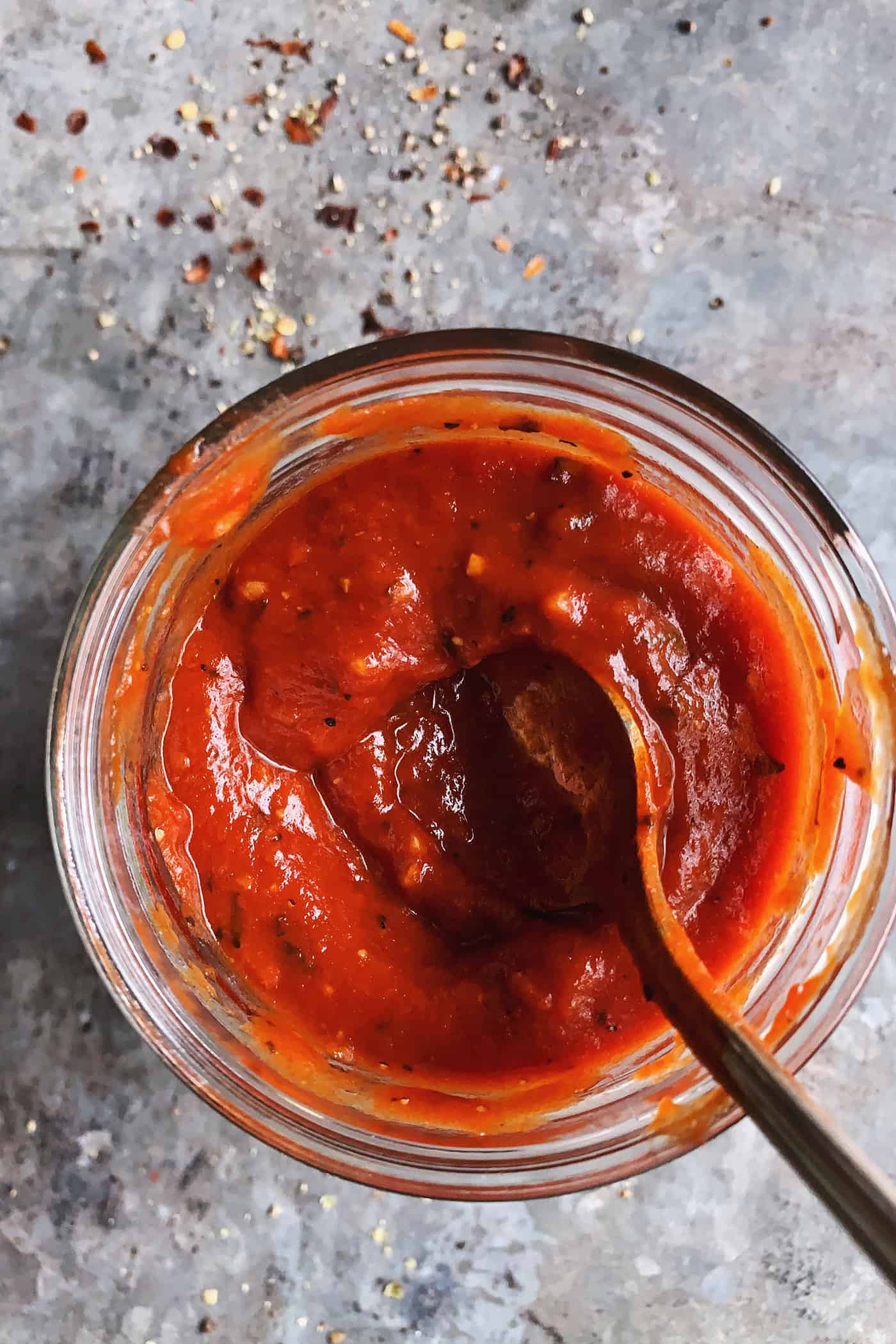 An easy recipe for the best homemade pizza sauce. It's a thick, tasty red sauce with fresh tomato flavor, made from simple ingredients! homemade sauce for pizza, in a jar with a spoon