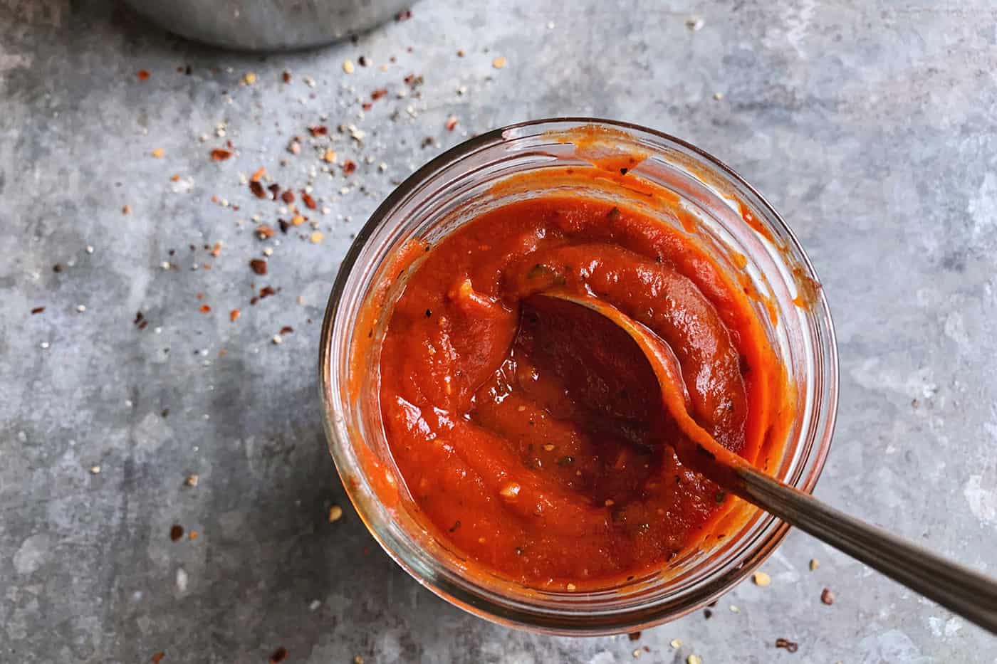 An easy recipe for the best homemade pizza sauce. It's a thick, tasty red sauce with fresh tomato flavor, made from simple ingredients! red sauce for pizza, in a jar with a spoon