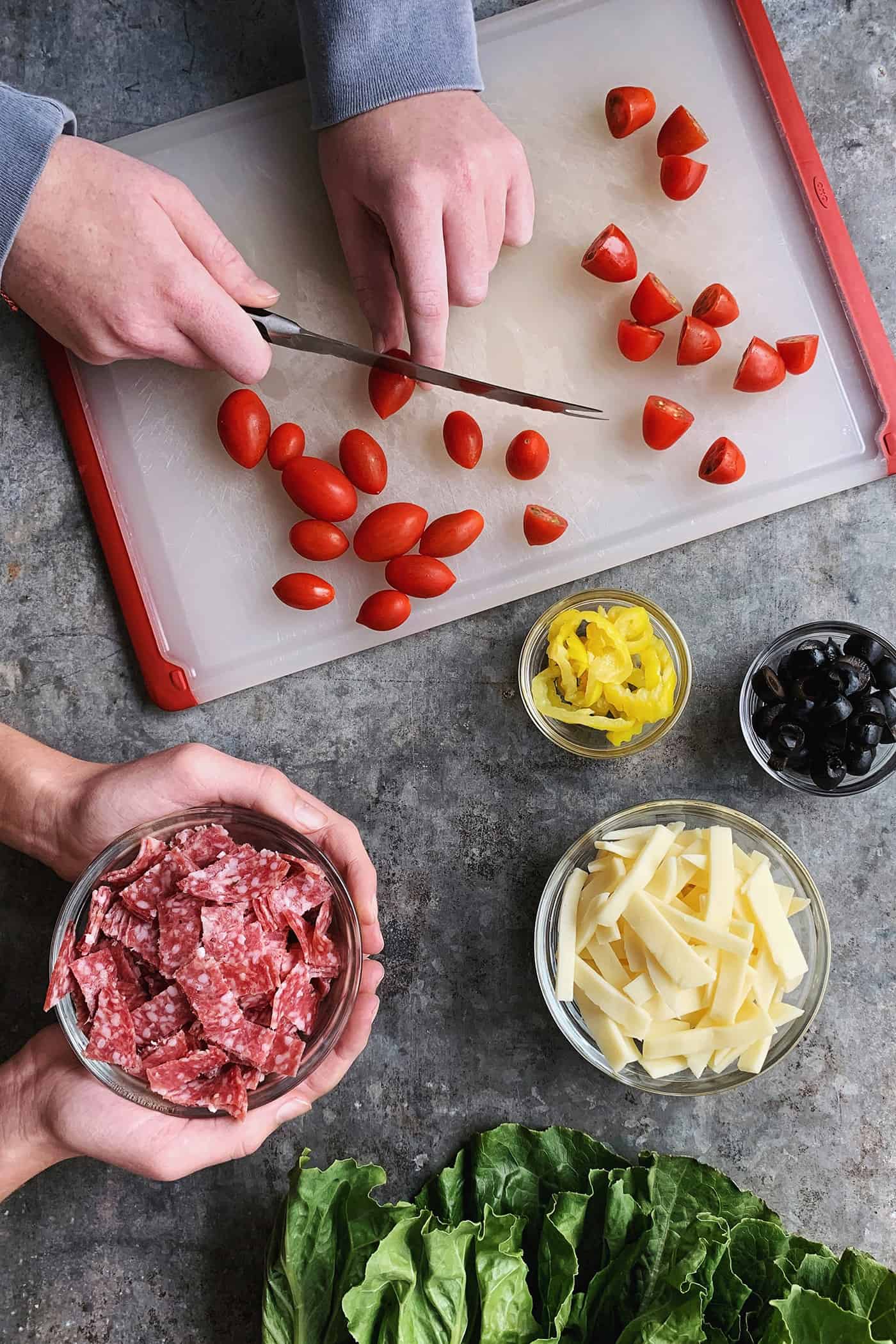 An easy recipe for the best homemade pizza sauce. It's a thick, tasty red sauce with fresh tomato flavor, made from simple ingredients! two people's hands, prepping a fresh Italian chopped salad