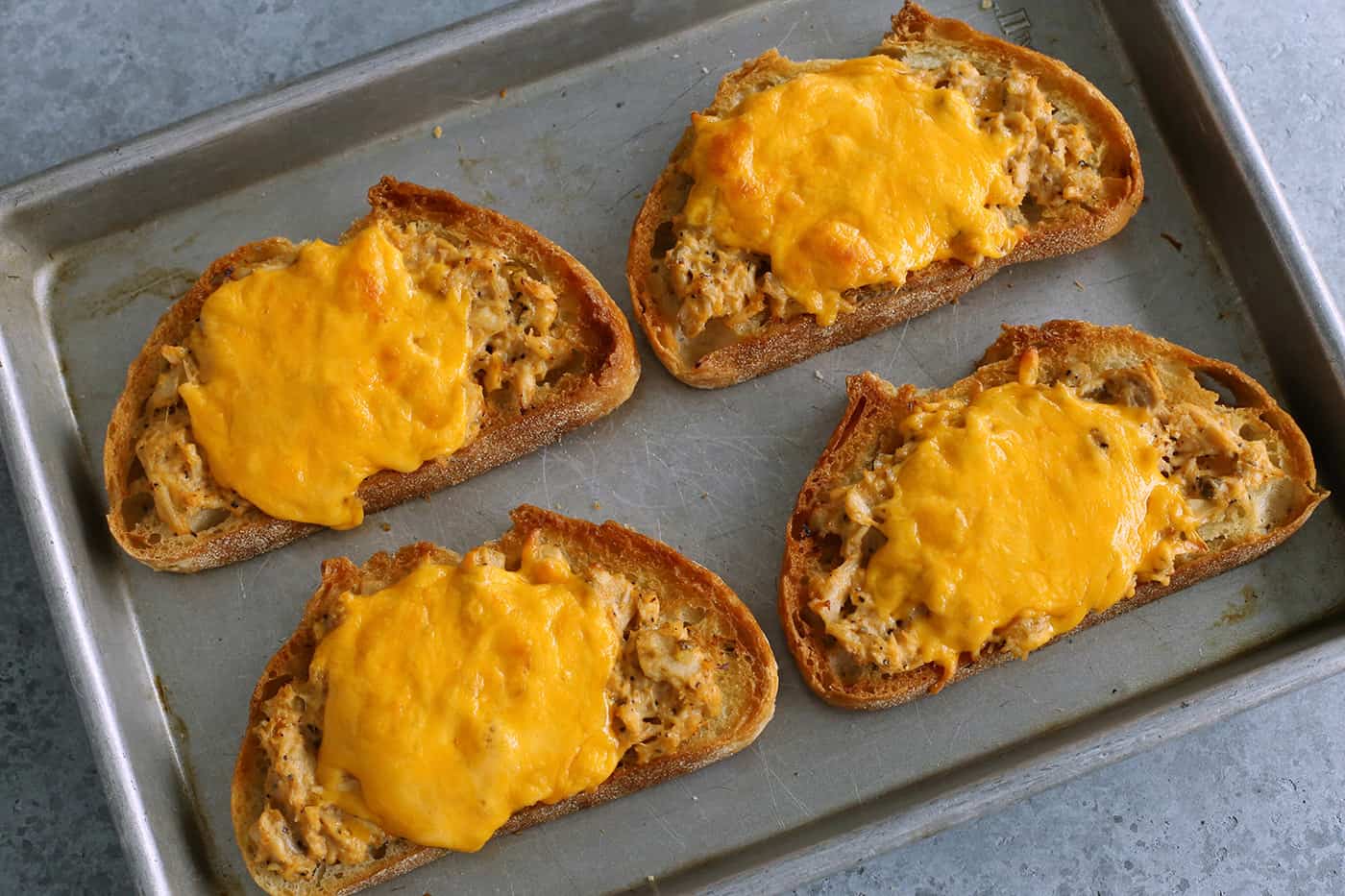 This spicy tuna melt recipe is a quick, easy hot sandwich with tuna, melty cheese, and spicy sriracha made warm and toasty in the oven! tuna melts on a sheet pan