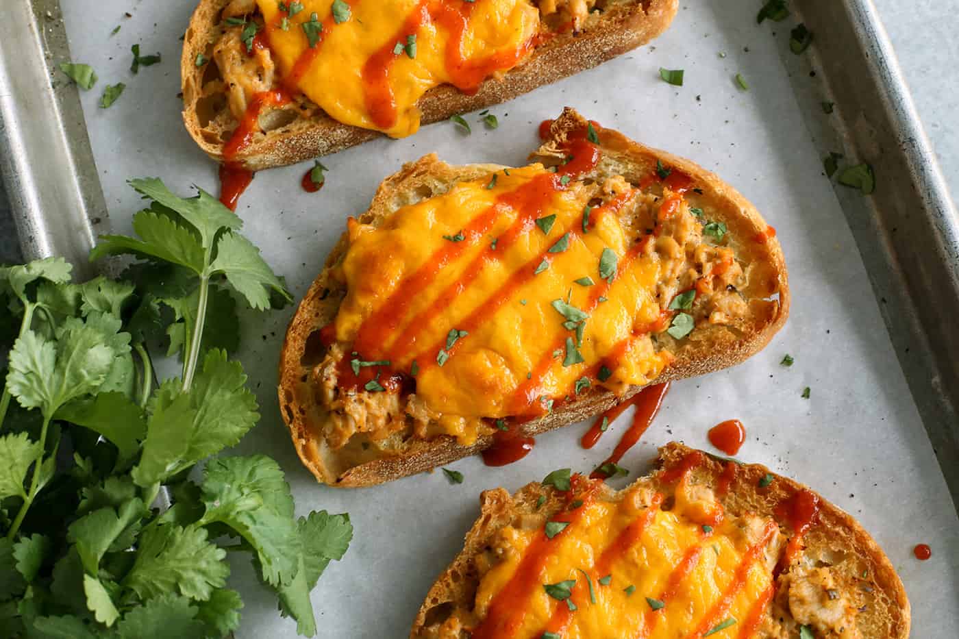 This spicy tuna melt recipe is a quick, easy hot sandwich with tuna, melty cheese, and spicy sriracha made warm and toasty in the oven! tuna melt sandwich with sriracha drizzle