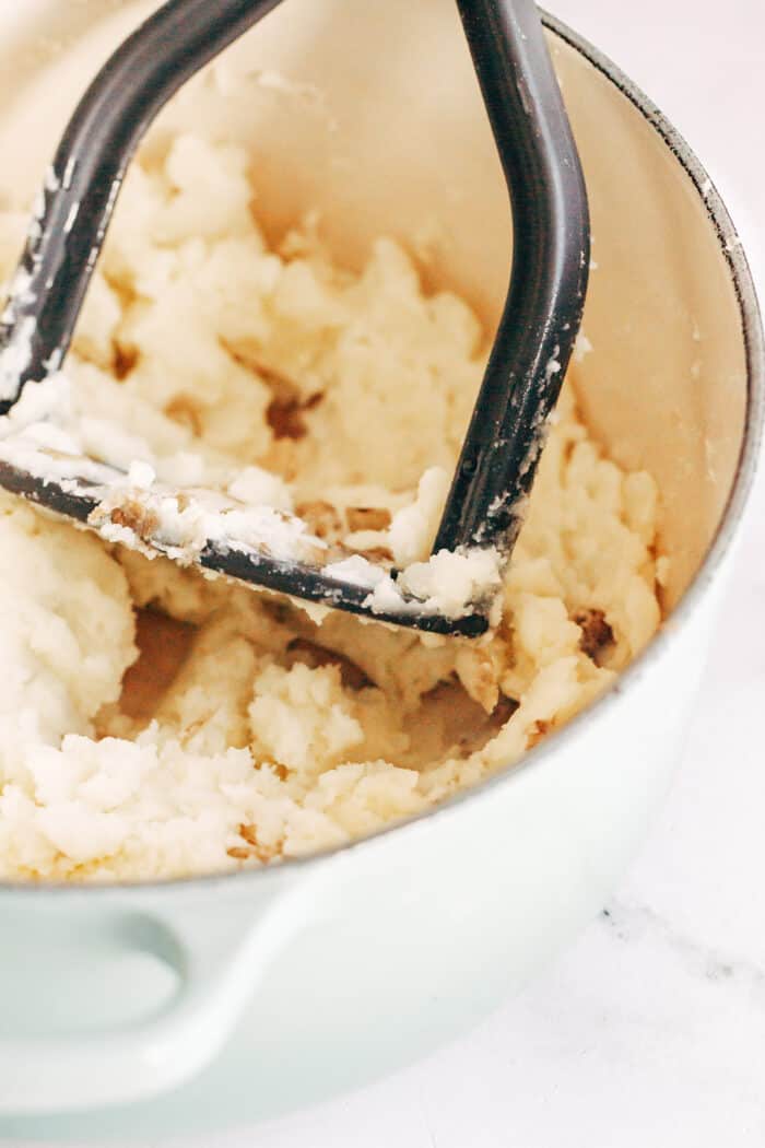 Using a hand-masher to make rustic, chunky mashed potatoes.