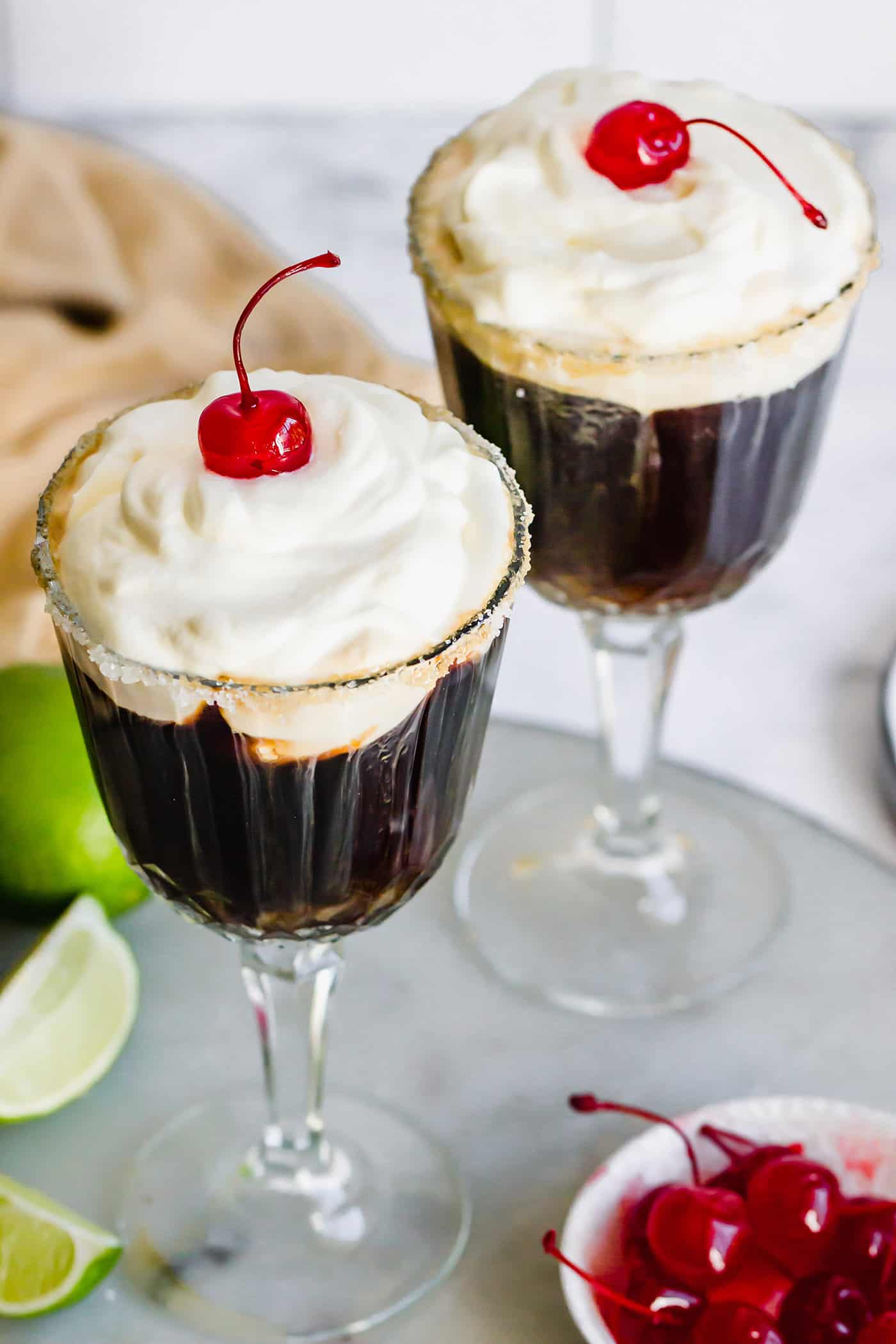 Mexican Coffee is a decadent dessert cocktail that's served hot. With tequila, Kahlua, and whipped cream, this recipe is a fun and beautiful way to top off a meal! top view of two glasses of a Mexican cocktail made with coffee, liqueurs, whipped cream, and maraschino cherries