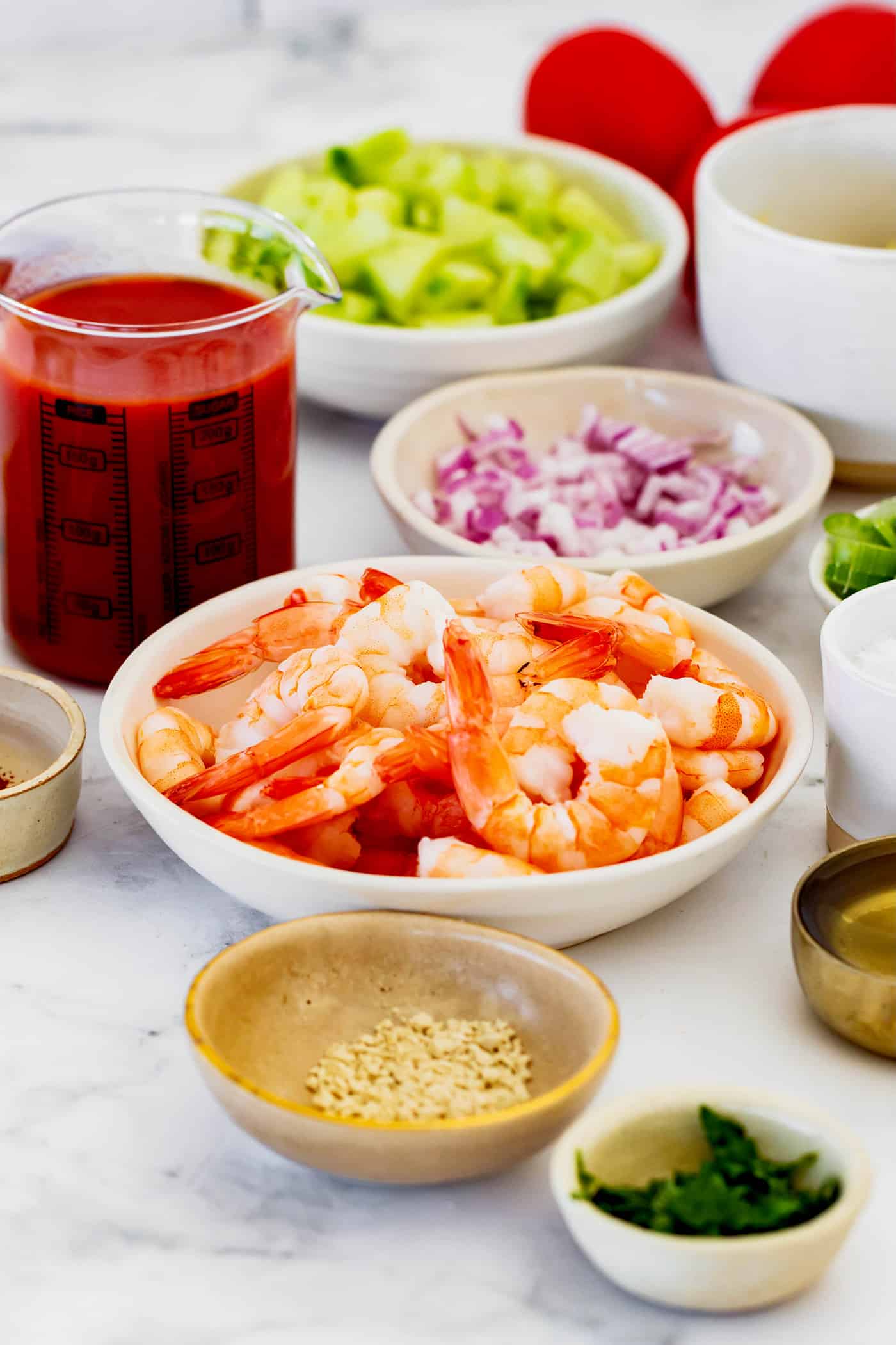 This Mexican shrimp cocktail recipe is a fun twist on a classic appetizer, featuring juicy shrimp and a spicy homemade cocktail sauce! ingredients for shrimp cocktail, including shrimp, diced avocado and red onion, and tomato juice