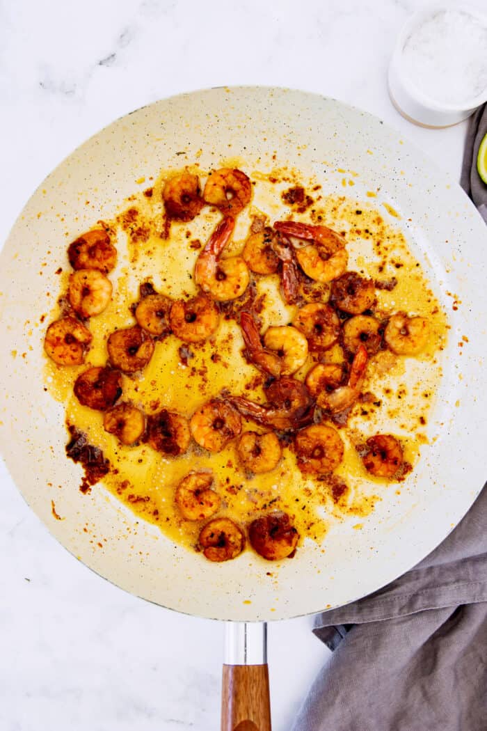 This Mexican shrimp cocktail recipe is a fun twist on a classic appetizer, featuring juicy shrimp and a spicy homemade cocktail sauce! shrimp sautéed in a white fry pan