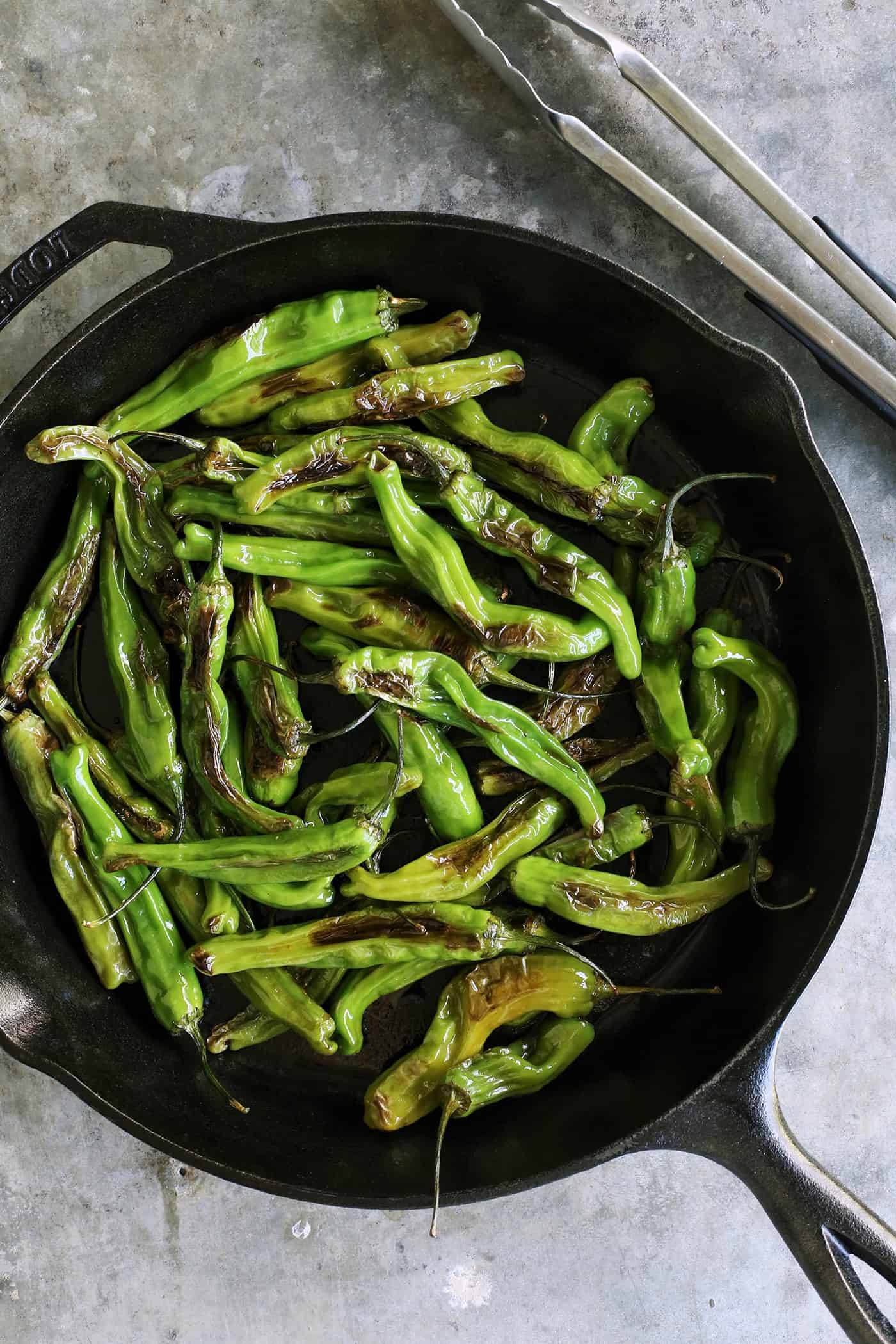 This Blistered Shishito Peppers recipe comes together quickly, with just a few ingredients - one of the easiest appetizers you'll ever make! blistered shishitos in a cast iron skillet