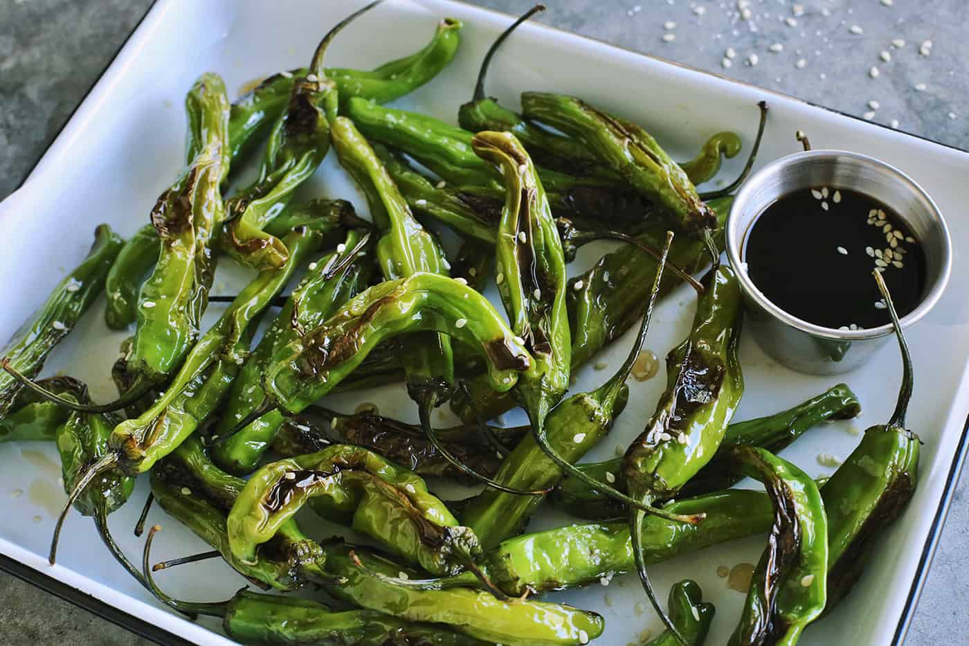 This Blistered Shishito Peppers recipe comes together quickly, with just a few ingredients - one of the easiest appetizers you'll ever make! blistered peppers and a cup of soy honey sauce for dipping