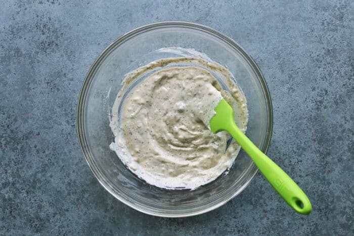 This crunchy, creamy coleslaw recipe is a favorite BBQ side. Serve it as a cooling accompaniment to grilled meats, tacos, or pulled pork! coleslaw dressing in a clear bowl, with a green spatula