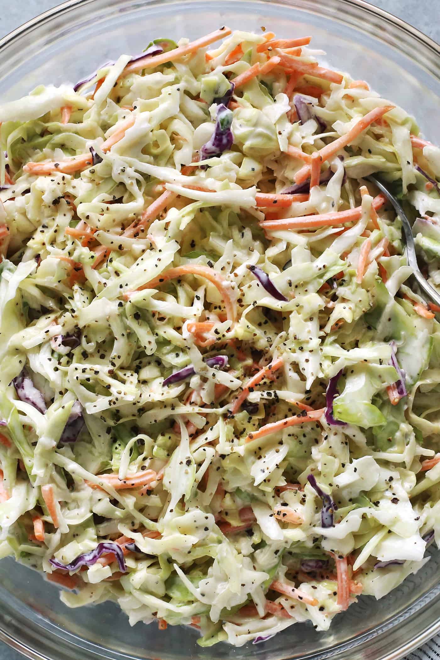 This crunchy, creamy coleslaw recipe is a favorite BBQ side. Serve it as a cooling accompaniment to grilled meats, tacos, or pulled pork! close-up photo of creamy coleslaw in a clear bowl