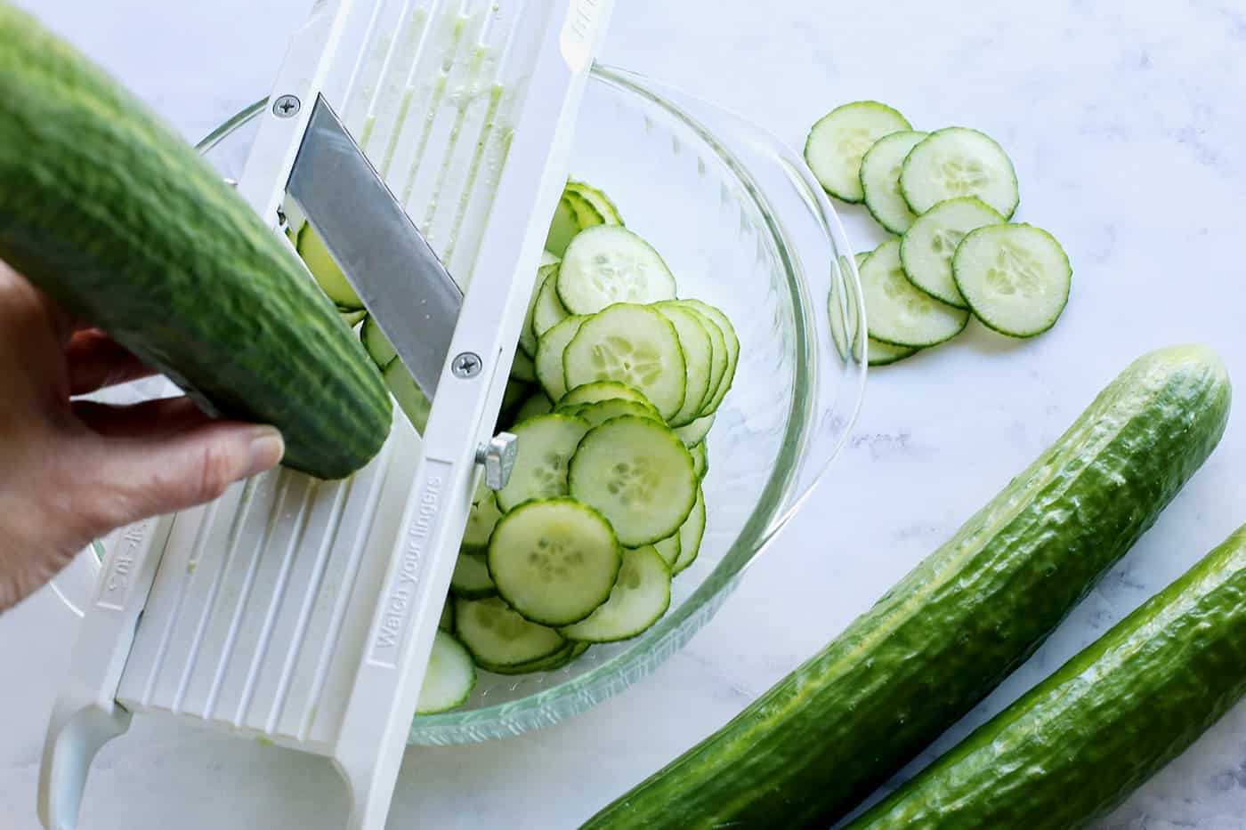 This easy cucumber salad recipe is a refreshing summertime side dish with thinly sliced cucumbers and onion, plus a tangy vinegar dressing. slicing cucumbers with a mandoline