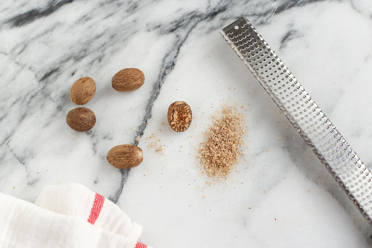 These homemade cranberry orange scones are perfectly flaky and great for a weekend breakfast or holiday brunch. They're easy to make too! Whole nutmeg next to freshly grated nutmeg and a metal grater on a marble countertop.