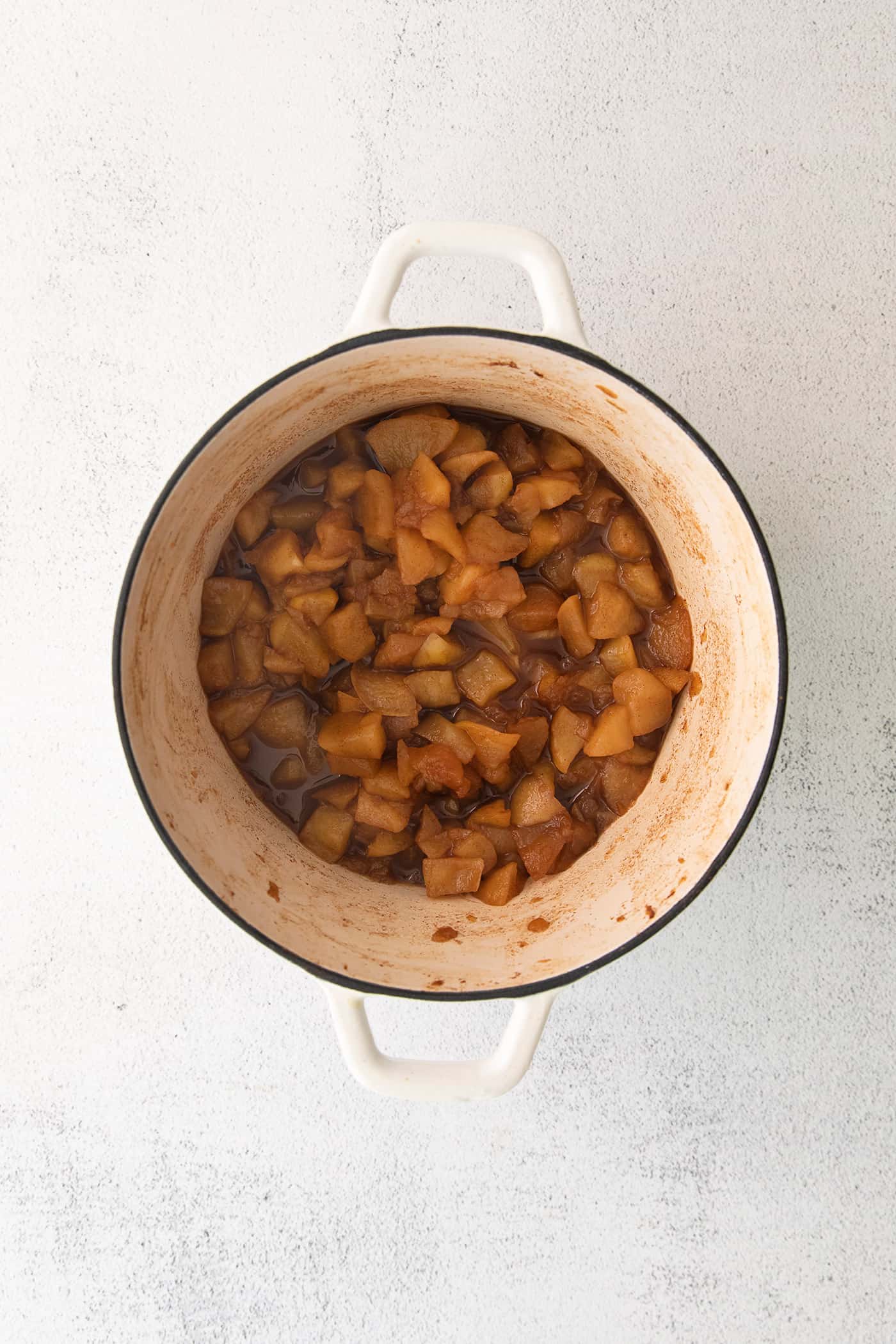 This easy homemade applesauce recipe can be made smooth or chunky, with simple refrigerator storage or canning for long-term pantry storage! chopped apples cooked and softened in a large white pot