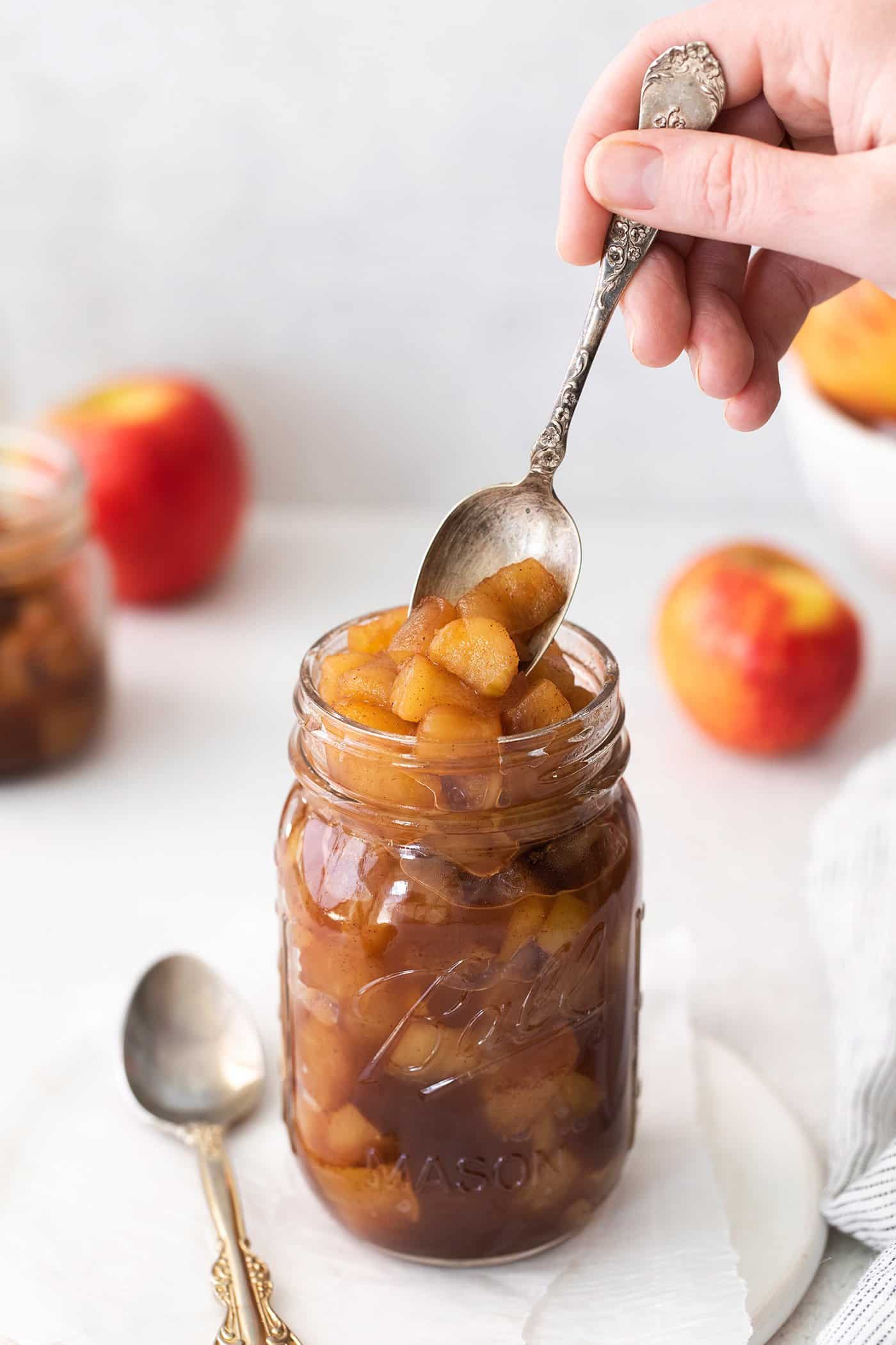 This easy homemade applesauce recipe can be made smooth or chunky, with simple refrigerator storage or canning for long-term pantry storage! a spoon dipping into a jar of homemade applesauce