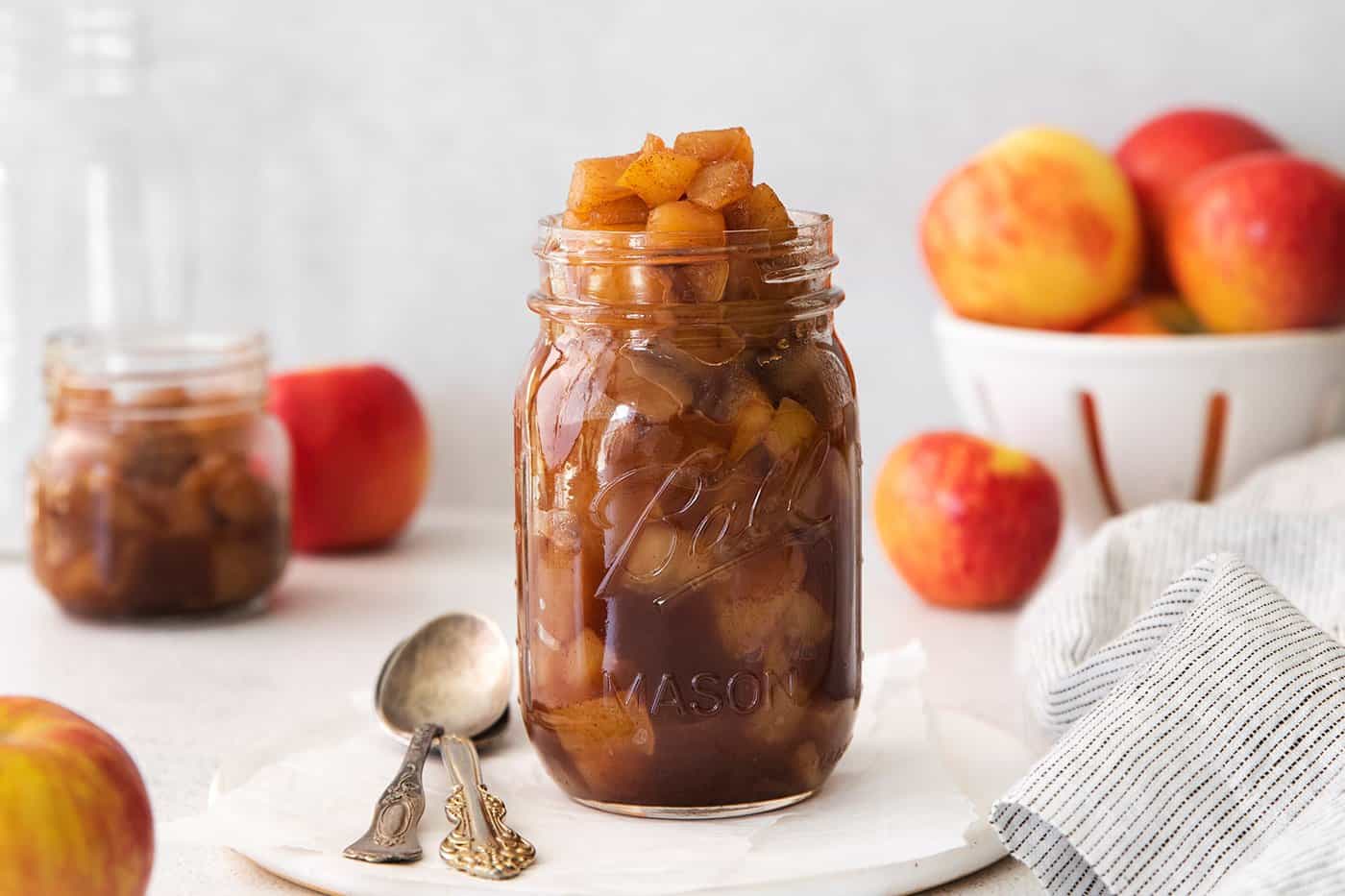 This easy homemade applesauce recipe can be made smooth or chunky, with simple refrigerator storage or canning for long-term pantry storage! a jar of homemade chunky applesauce, surrounded by fresh apples