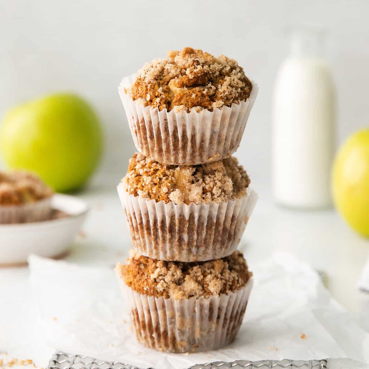 Make moist, tender apple muffins studded with juicy apple bites! Topped with cinnamon streusel, these easy muffins are great for fall baking. 3 muffins with apples and crumble topping, stacked on top of each other