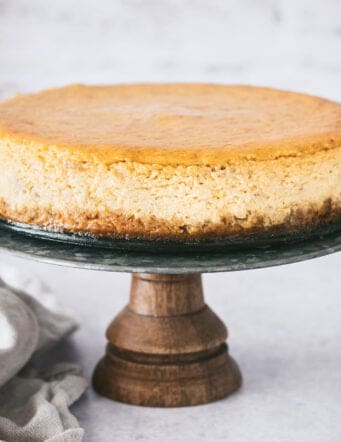 Pumpkin cheesecake on a wooden cake stand.