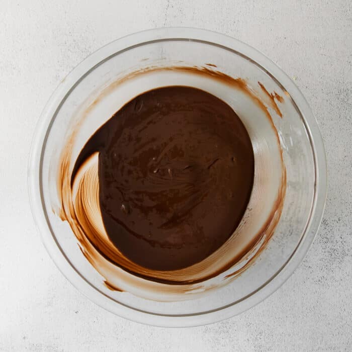 A clear bowl of melted chocolate chips, peanut butter, and butter.