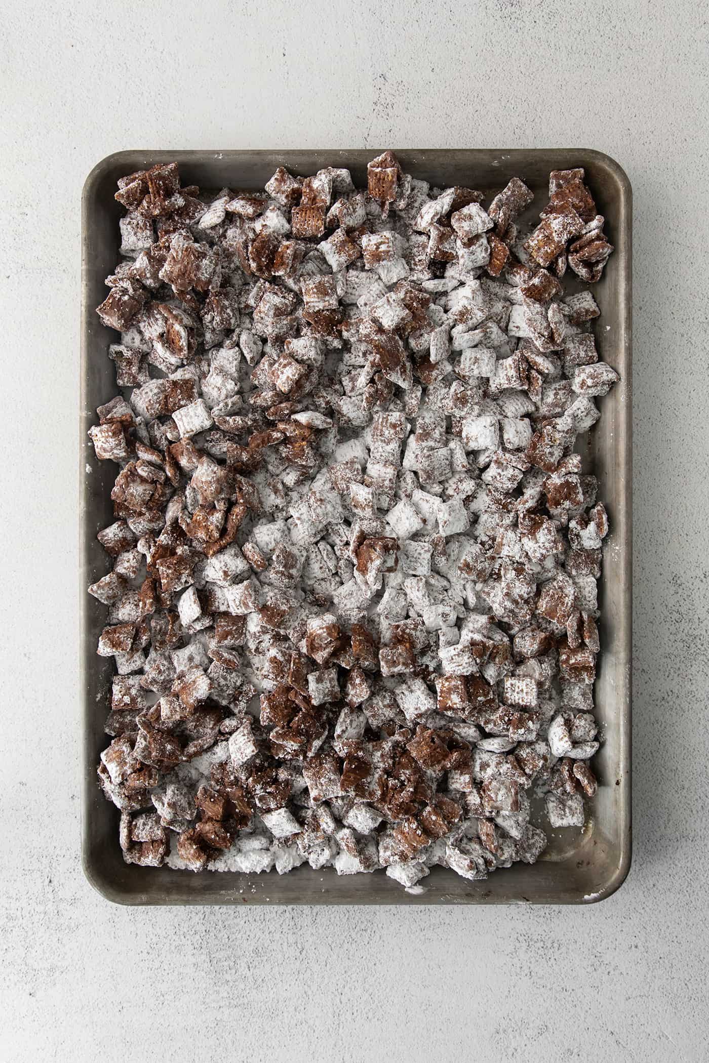 Puppy chow cooling on a large rimmed pan.