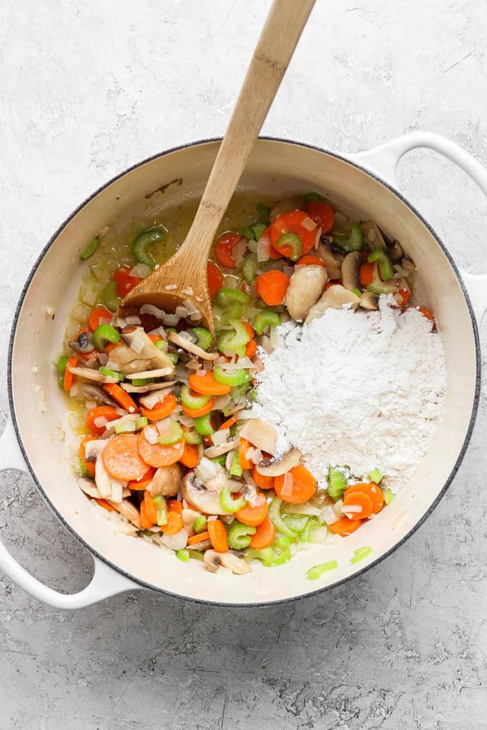 Overhead view of flour added to vegetables in Dutch oven