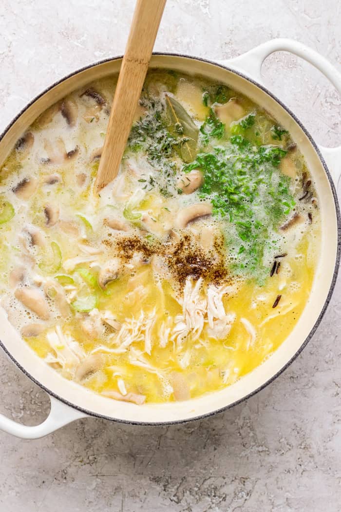 Overhead view of chicken wild rice soup simmering in pot with wooden spoon