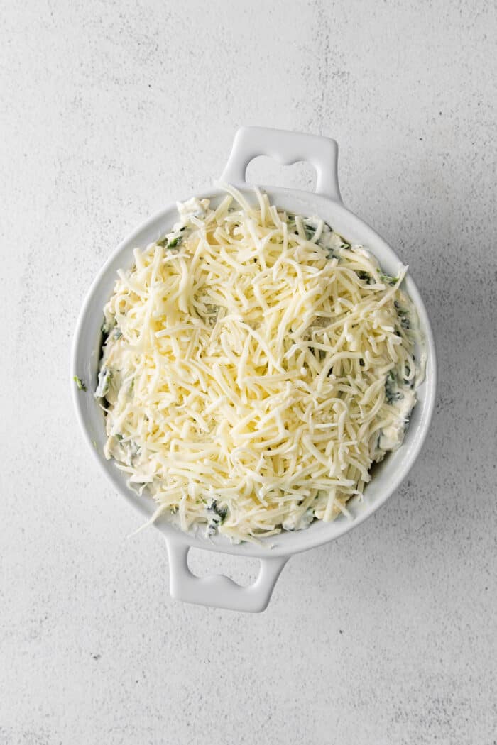Creamy and cheesy, this baked Spinach Artichoke Dip recipe is a classic party dip. Serve hot with chips, pita, or veggies. Irresistible! Spinach and artichoke dip in a dish topped with mozzarella