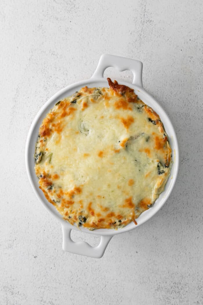 Creamy and cheesy, this baked Spinach Artichoke Dip recipe is a classic party dip. Serve hot with chips, pita, or veggies. Irresistible! Overhead view of a dish of spinach artichoke dip