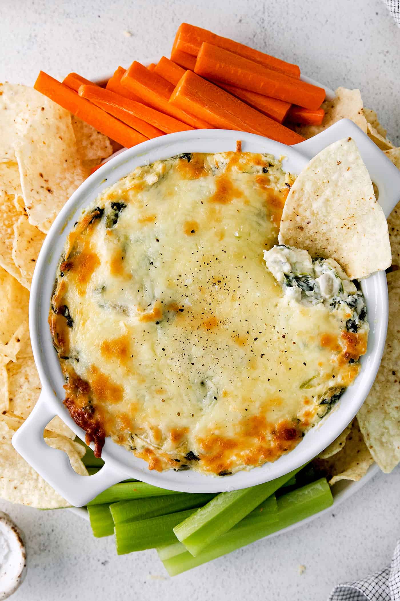 Creamy and cheesy, this baked Spinach Artichoke Dip recipe is a classic party dip. Serve hot with chips, pita, or veggies. Irresistible! Overhead view of a bowl of spinach artichoke with