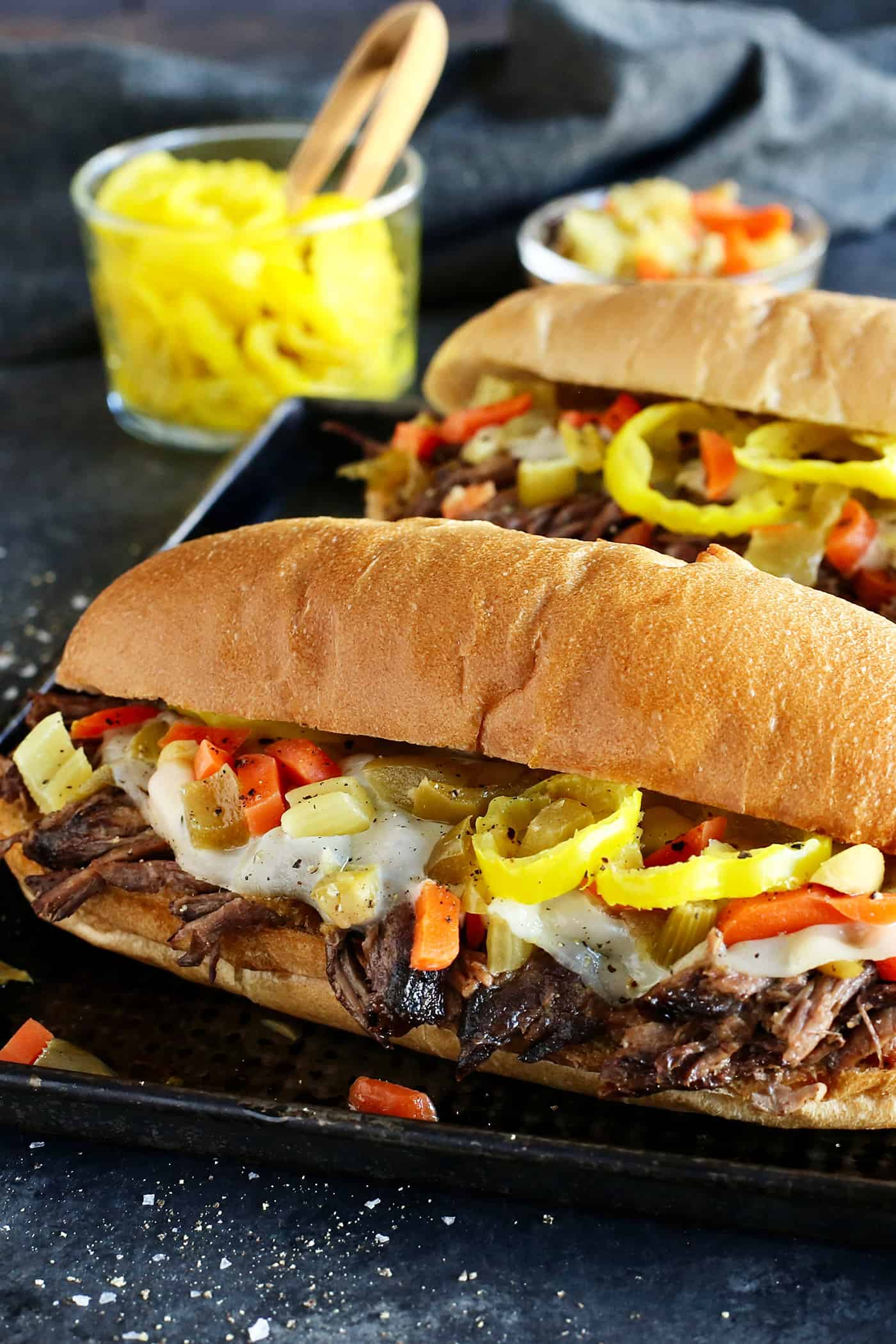 Slow cooker Italian beef in a hoagie sandwich with provolone cheese and peppers