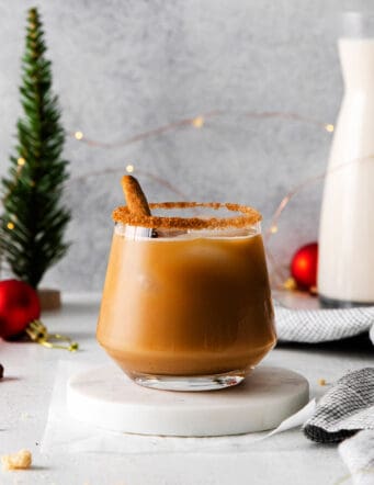 a white Russian cocktail with eggnog and cinnamon syrup, plus Christmas decorations