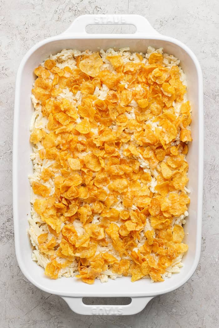This cheesy hashbrown casserole recipe is an easy side dish that’s ready in under an hour. You'll love the crispy cornflake topping! Overhead view of cheesy hashbrown casserole before baking