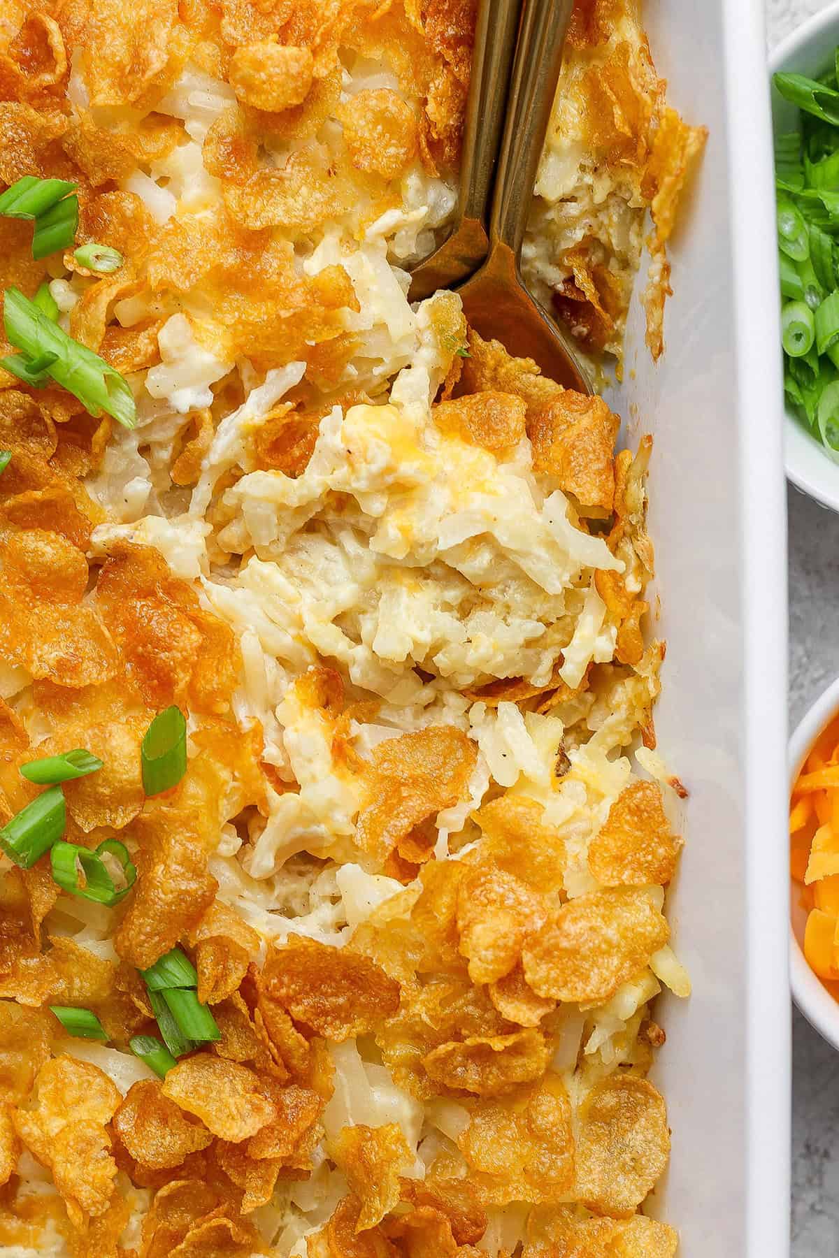 This cheesy hashbrown casserole recipe is an easy side dish that’s ready in under an hour. You'll love the crispy cornflake topping! Overhead view of cheesy hashbrown casserole in baking dish