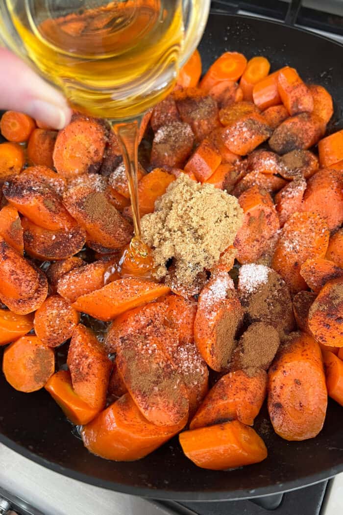 Tossed in a mixture of cinnamon, brown sugar, and honey, these Candied Carrots are perfectly sweet and savory. A quick & easy side dish! pouring honey over cut carrots