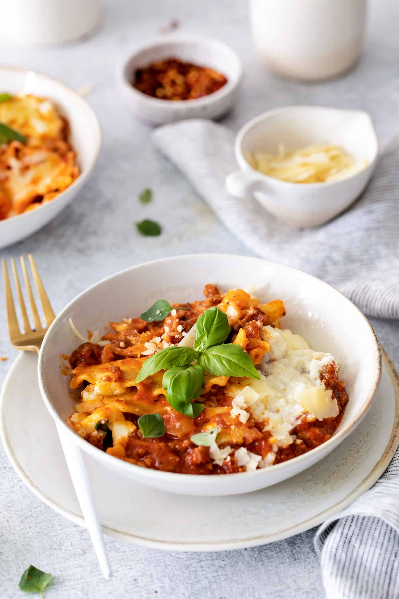 This skillet lasagna recipe has all the classic lasagna ingredients, without the extra dishes and layering! Perfect for weeknight dinners. Lasagna in a bowl topped with fresh basil leaves.