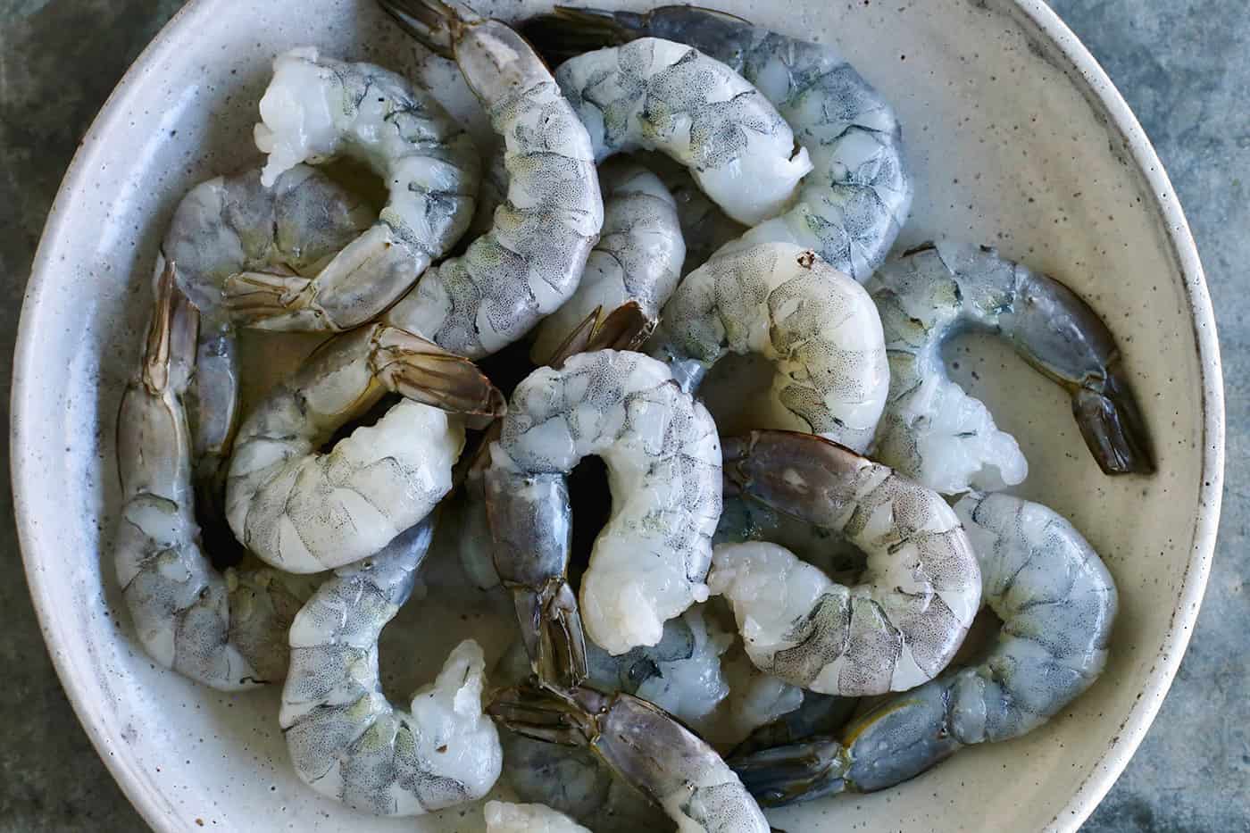 These 18 easy shrimp recipes are simple to make & guaranteed to impress! Learn everything you need to know about shrimp, plus how to cook it. Raw shrimp in a white bowl