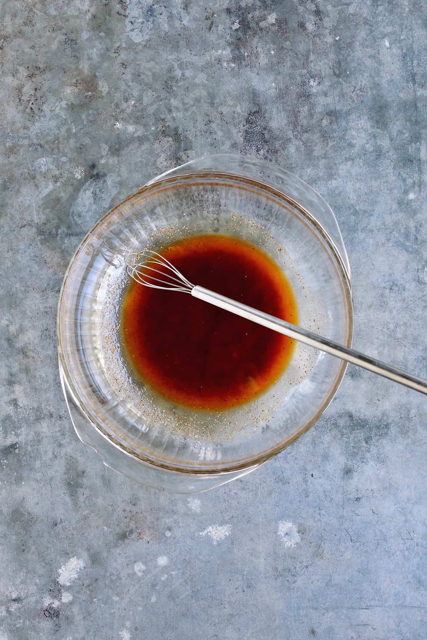 Tossed with olive oil and a few spices, this easy shrimp cocktail is perfectly flavored and grilled until just charred. So good! Olive oil and spices whisked in a glass bowl.