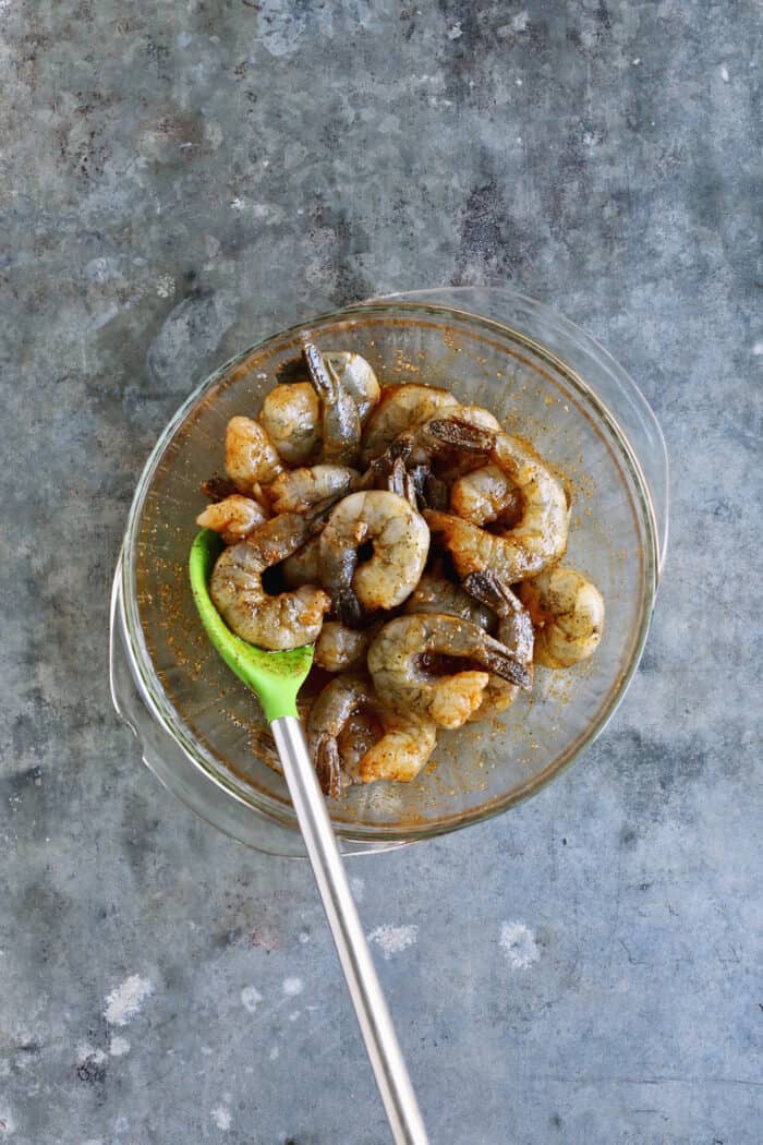 Tossed with olive oil and a few spices, this easy shrimp cocktail is perfectly flavored and grilled until just charred. So good! Grilled shrimp coated with a marinade in a glass bowl.