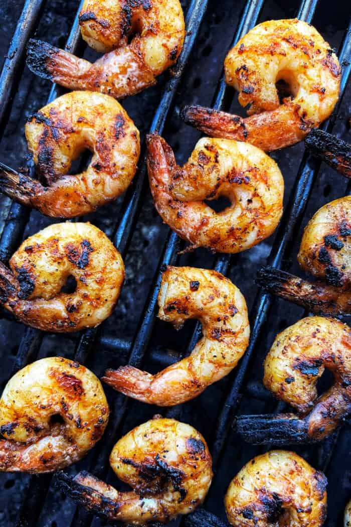 Tossed with olive oil and a few spices, this easy shrimp cocktail is perfectly flavored and grilled until just charred. So good! Overhead view of jumbo shrimp on a grill.