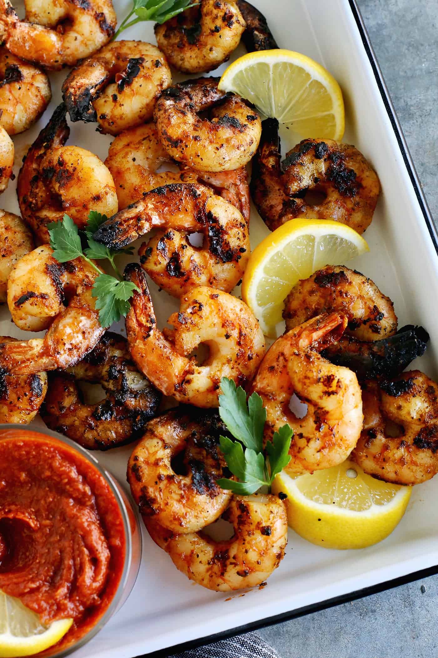 Tossed with olive oil and a few spices, this easy shrimp cocktail is perfectly flavored and grilled until just charred. So good! Overhead view of grilled shrimp cocktail.
