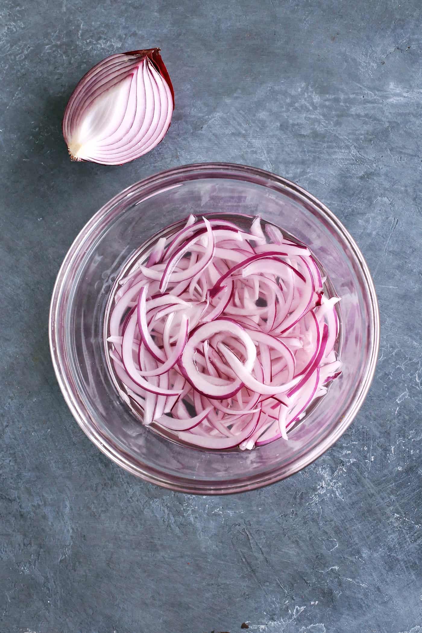 With just the right amount of heat, this Easy Shrimp Aguachile features shrimp marinated in lime juice and then tossed in a spicy marinade. Sliced red onions in a bowl with vinegar
