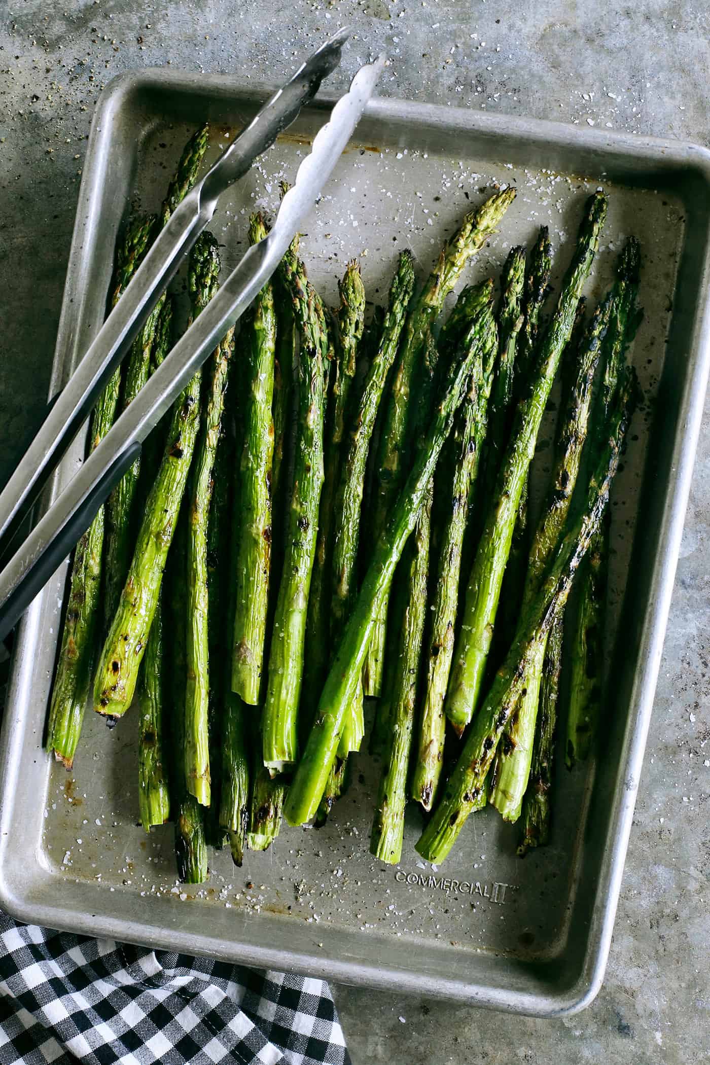 With just 2 ingredients, this Grilled Asparagus is an easy side dish that can be prepared in just 20 minutes. Overhead view of asparagus in a sheet pan with tongs
