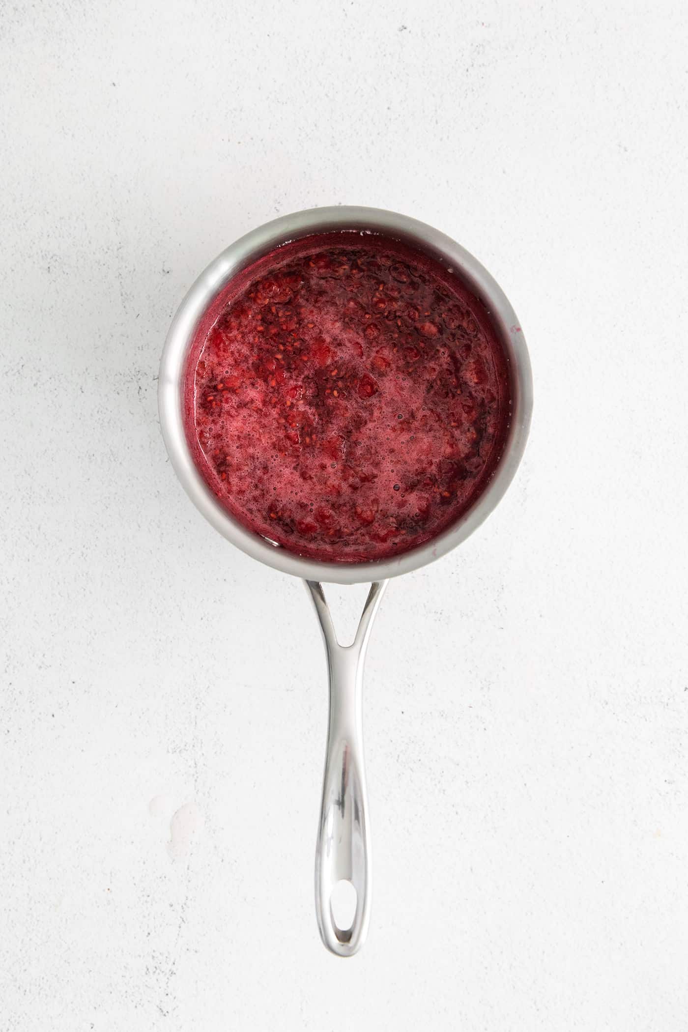 Sweet, bright, and intensely fruity this Raspberry Sauce makes a great topping for angel food cake, cheesecake, ice cream, and more. Raspberry sauce in a saucepan