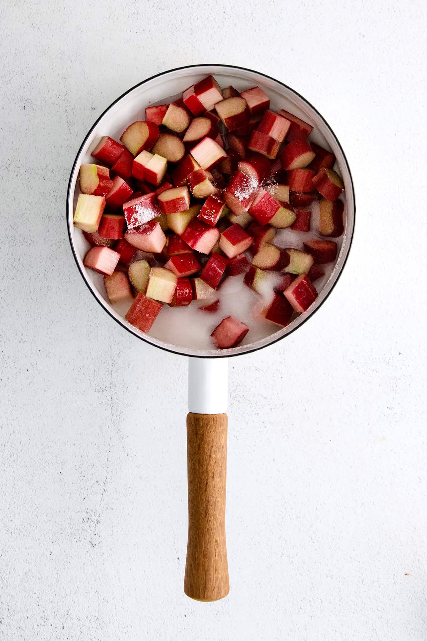 With just 3 ingredients - sugar, water, and rhubarb - you can make this sweet and tart Rhubarb Sauce. Use on ice cream, cake & more. Pieces of rhubarb and sugar in a sauce pan