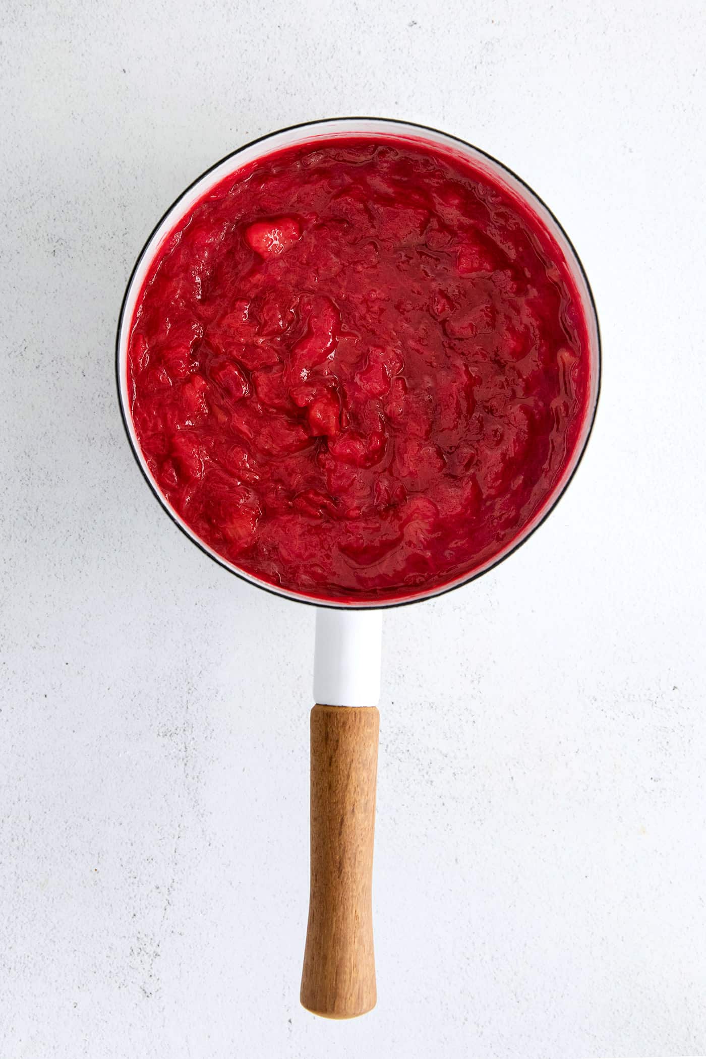 With just 3 ingredients - sugar, water, and rhubarb - you can make this sweet and tart Rhubarb Sauce. Use on ice cream, cake & more. Rhubarb sauce in a saucepan