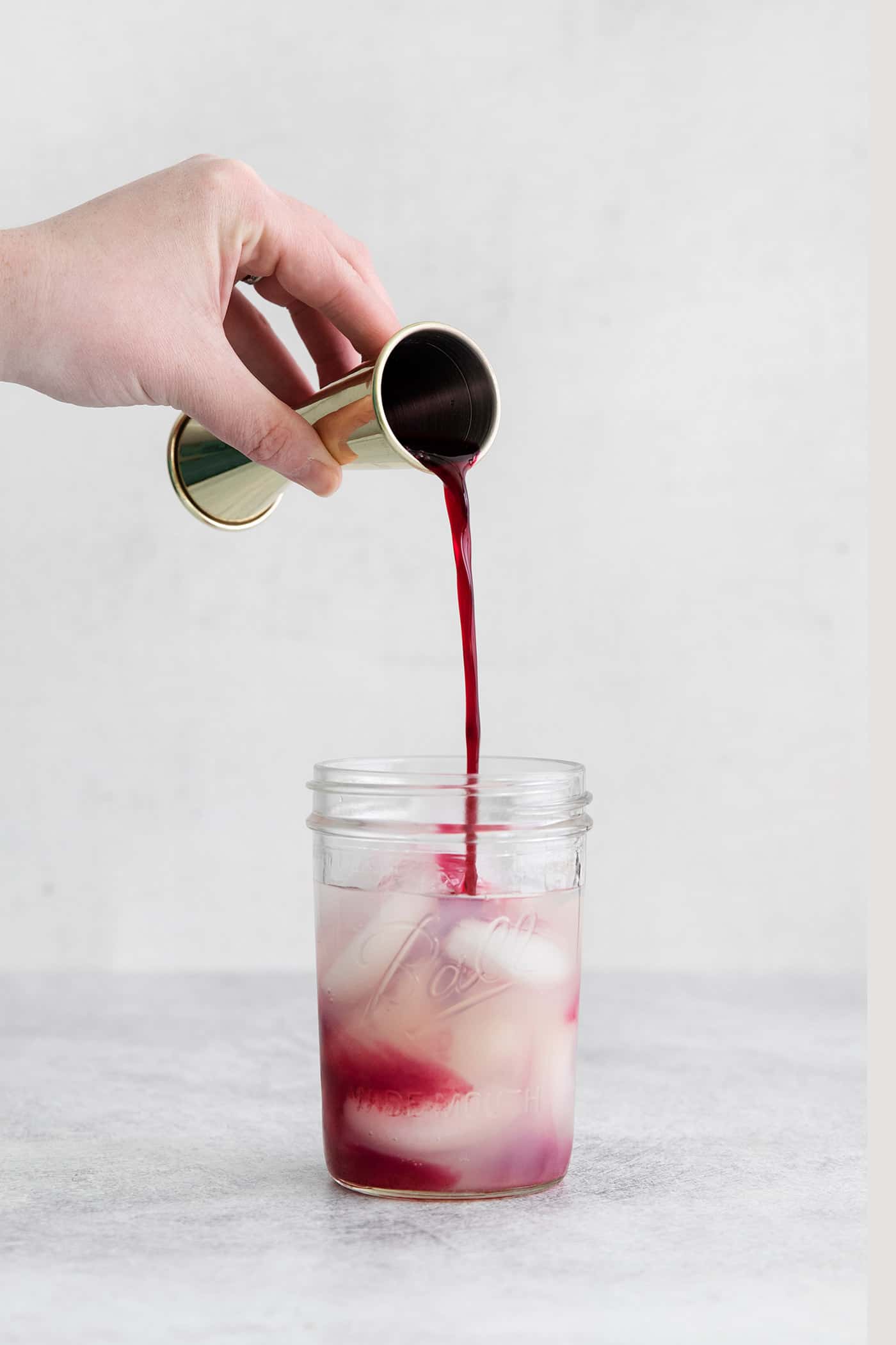 Made with flavored simple syrup, this Blueberry Margarita is just the fruity cocktail for summer. Sweet but tart and super refreshing! Blueberry simple syrup being poured into a mason jar with ice and tequila