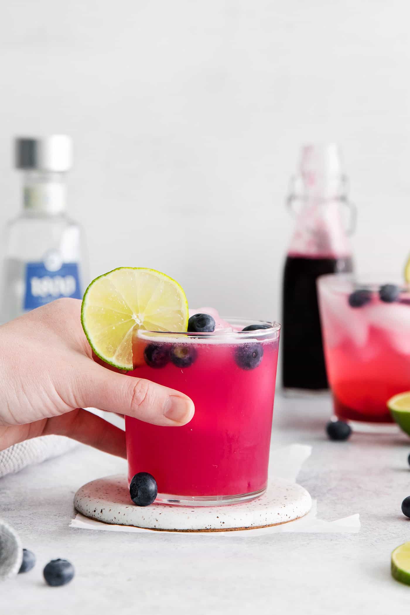 Made with flavored simple syrup, this Blueberry Margarita is just the fruity cocktail for summer. Sweet but tart and super refreshing! A hand holding a blueberry margarita
